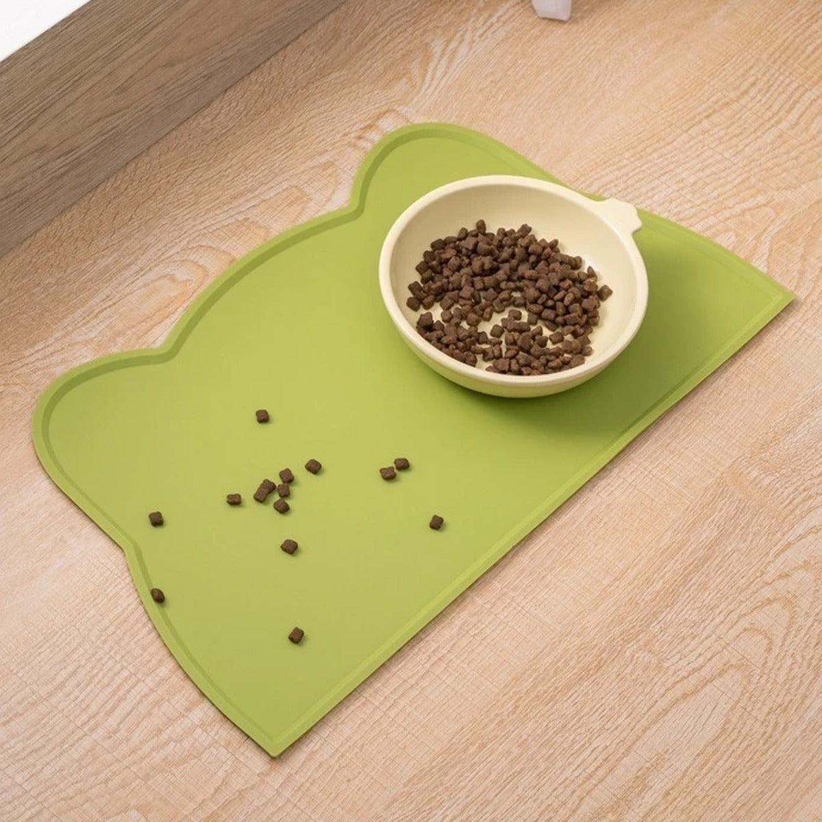 Croquettes tombées qui restent sur le tapis de gamelle vert